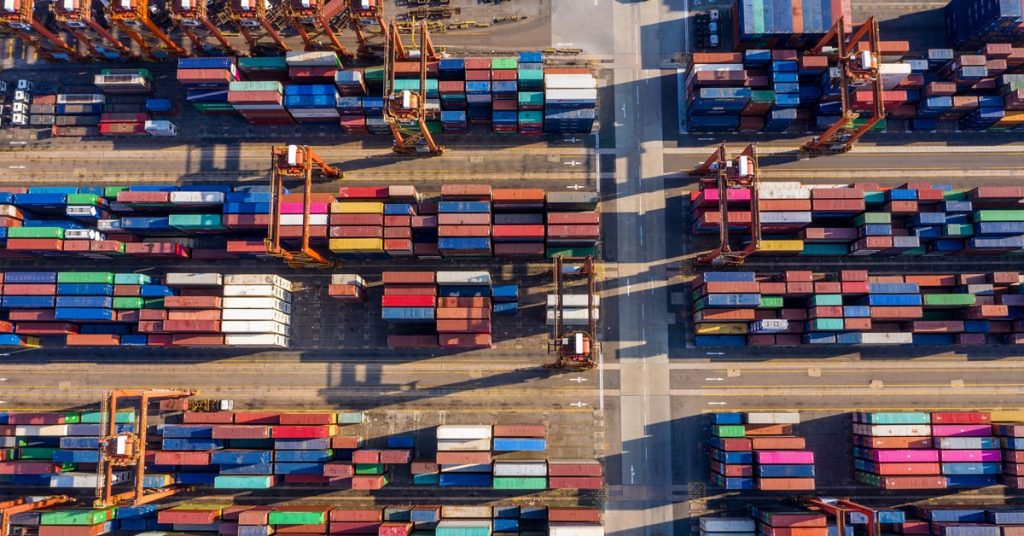 Aerial view of supply chain in action, dozens of colorful shipping containers at a port