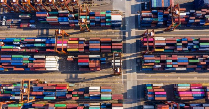 Aerial view of supply chain in action, dozens of colorful shipping containers at a port